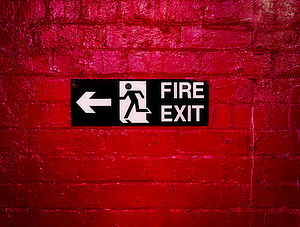 Sign Informing about the fire escape hung on a brick wall painted red.